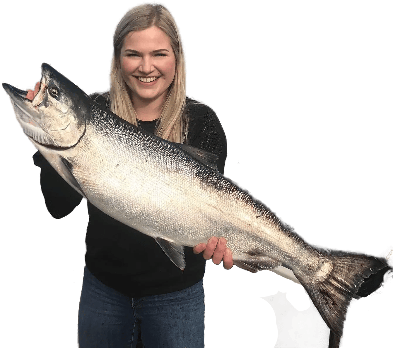 Person smiling, holding a large fish, wearing a black top and jeans, isolated on a transparent background.